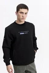 Buzo negro de algodón con cuello redondo, puños y cintura elásticos. Presenta un pequeño estampado frontal con texto en azul claro.