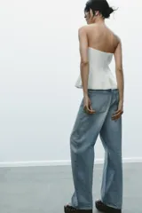 Top color amarillo claro, sin mangas y con escote recto. El bajo tiene un acabado peplum.