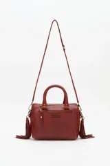 Bolso de mano tipo doctor bag o bowling bag, color marrón cuero, con diseño acolchado en rombos y tachas doradas. Posee doble asa de mano y un dije colgante de flecos largos de cuero marrón.