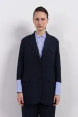 Blazer azul marino con diseño cuadrillé, corte clásico, solapas de muesca, cierre frontal con dos botones, bolsillos de parche y confección en tejido de lino y viscosa.