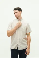 Camisa de manga corta confeccionada en una mezcla de lino y algodón, con cuello clásico, cierre frontal de botones y bolsillo en el pecho con logo bordado.