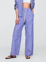 Pantalón de popelina con diseño de rayas verticales en azul y blanco, de corte recto y holgado con cintura elástica y cordón ajustable.