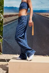 Pantalón de jean azul denim con tiro bajo, corte oversize y grabado láser con monograma.
