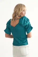 Blusa negra de seda con escote en V y mangas abullonadas cortas. Tiene cierre lateral.