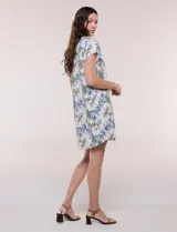 Vestido corto de lino color celeste con cuello camisero, escote en V, mangas cortas, bolsillos laterales invisibles y silueta holgada.
