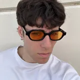 Gafas de sol unisex con montura ovalada negra y lentes naranjas.