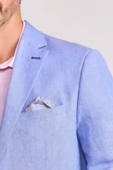 Blazer sport de corte entallado en color celeste, con solapas clásicas, cierre frontal de un botón y bolsillos laterales con solapa. Presenta un pañuelo de bolsillo estampado y botones decorativos en los puños.