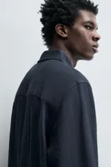 Camisa de corte relajado confeccionada en tejido fluido con mezcla de viscosa. Presenta cuello solapa, cierre frontal con botones y manga larga con puños abotonados.