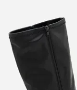 Bota de caña alta Satinato en color negro, confeccionada en material sintético con acabado liso. Presenta un diseño de punta fina y tacón tipo anabela, con una estructura ajustada a la pierna.
