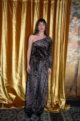 Mono largo de terciopelo negro con estampado paisley en tonos borgoña, verde y blanco. Diseño de un solo hombro con manga larga abullonada y pantalón palazzo.