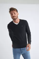 Sweater de tejido de punto color beige, con escote en V, mangas largas y puños y dobladillo acanalados. Presenta un pequeño logo bordado en el pecho.