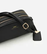 Cartera pequeña de hombro marca Satinato, confeccionada en PU con textura granulada. Presenta doble compartimento con cierre de cremallera metálica dorada, correa larga ajustable y un dije decorativo metálico con el logo de la marca.