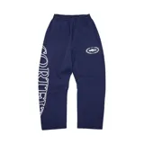 Pantalón de jogging azul marino con estampado gráfico blanco en la pierna derecha y logo circular en la pierna izquierda. Cuenta con cintura elástica y bolsillos laterales.