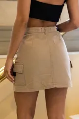 Minifalda color beige con bolsillos laterales y cierre frontal con botón y cremallera.