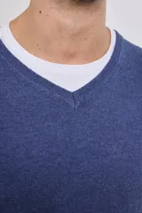 Suéter de punto color azul marino con cuello en V y manga larga. Se lleva sobre una remera blanca con cuello en V.