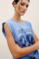 Musculosa celeste con hombreras estructuradas, cuello redondo y estampa frontal con la inscripción "LADY LUCK" y el número "28" en color azul oscuro.