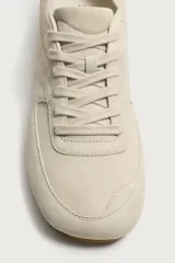 Zapatilla de cordones con parte superior fabricada en piel con acabado serraje, detalle de pespuntes y suela ultrafina a tono.