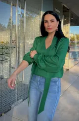 Blusa de satén color verde, con cuello en V y detalle de lazo integrado al cuello. Presenta mangas largas abullonadas con puños ajustados.