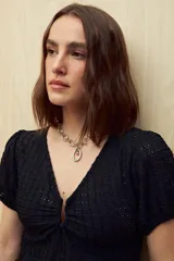 Top negro de textura tramada, con escote en V y frunce central. Posee mangas cortas con elástico y un ruedo con volado sutil.