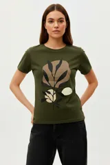 Remera de algodón color verde oliva, con cuello redondo y mangas cortas. Presenta un estampado frontal con diseño botánico abstracto en tonos tierra y negro.