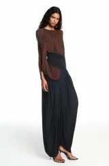 Mono largo bicolor con cuerpo drapeado en color marrón y parte inferior tipo pantalón bombacho en color negro. Presenta un diseño sin mangas con un hombro descubierto y una banda ancha ajustada en la cintura.
