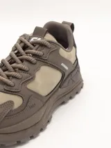 Zapatillas urbanas de estilo trekking, color taupe (marrón claro/beige), con suela gruesa y detalles superpuestos en material sintético y textil.