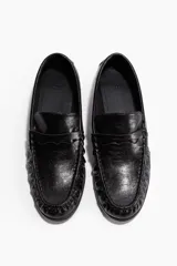 Mocasines negros de cuero con costura tradicional en la puntera y tira de adorno tipo penny en el empeine.
