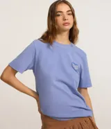 Remera oversize de manga corta y cuello redondo, color celeste, con gran estampa romántica en la espalda con diseño de corazón, ángeles y tipografía.