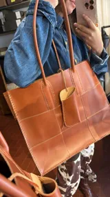 Bolso tote grande de cuero natural en color marrón, con diseño de piezas unidas mediante costuras visibles y asas de hombro.