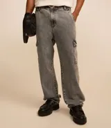 Pantalón de jean modelo baggy con bolsillos cargo laterales, cintura con trabillas y cierre frontal con botón y cremallera.