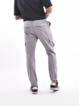 Pantalón jogger cargo color verde militar con cintura elástica ajustable con cordón, bolsillos laterales y bolsillos cargo con solapa en los muslos.