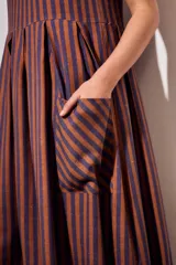 Vestido midi sin mangas, con diseño a rayas en tonos marrón y azul, cuello redondo y bolsillos laterales amplios.