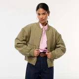 Chaqueta bomber acolchada color verde oliva, con cuello, puños y bajo acanalados. Presenta cierre frontal con botones a presión, bolsillos delanteros con solapa y mangas largas extraíbles.