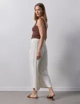 Pantalón de lino color crudo, de corte ancho y largo cropped, con bolsillos laterales.