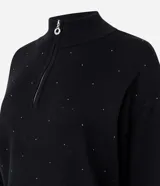 Suéter de punto color gris con cuello alto y medio cierre frontal. Presenta mangas largas con puños ajustados y una sutil aplicación de brillos en la parte frontal.