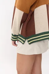 Cardigan de punto con diseño de bloques de color en tonos marrón, beige y verde. Presenta cuello redondo, cierre frontal con botones, mangas largas con hombros caídos y logo bordado en el frente.