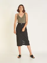 Falda midi color beige, de tiro alto con elástico en la cintura trasera, cierre y botón delantero. Tiene bolsillos delanteros y bolsillos cargo a los costados, con tajo en el delantero.