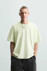 Camiseta de corte relaxed fit, color verde lima pálido, con cuello redondo y manga corta. Presenta un estampado sutil en el pecho.