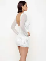 Vestido corto de manga larga, color blanco con estampado de puntos brillantes plateados. Presenta un diseño ajustado al cuerpo con cuello redondo.