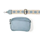 Bandolera celeste de cuero con correa ancha de tela con diseño geométrico en tonos celeste, beige y blanco.