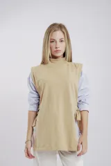 Chaleco color beige de tela tipo gamuza, con cuello alto y lazos en ambos laterales.