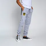 Pantalón de jogging negro con puños ajustados en los tobillos y cordón en la cintura. Presenta un escudo bordado en amarillo y negro en la pierna izquierda.