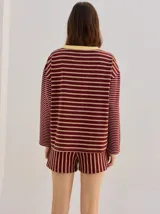 Remera manga larga de corte oversize y cuello redondo, con diseño a rayas horizontales en tonos claros y verde militar, y detalle de bordado frontal.