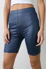 Calza corta tipo biker de tiro alto, confeccionada en tela engomada de acabado brillante con cintura elástica.
