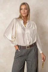 Camisa de organza en color blanco, con cuello mao, cierre frontal de botones y mangas largas estilo murciélago con puños elásticos. Presenta un diseño holgado y fluido.
