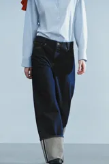Jeans de tiro bajo y pernera ancha, confeccionados en denim azul oscuro con pespuntes en contraste. Cuentan con un diseño de cinco bolsillos, cierre frontal con cremallera y botón metálico, y destacan por su amplio doblando en el bajo que deja ver el revés de la tela con detalles de costura selvedge.