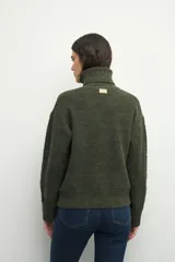 Polera de cuello alto con textura tramada, manga larga con puños acanalados y diseño holgado.