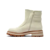 Bota de caña media color beige, confeccionada en material tipo gamuza, con suela track de goma en tono terracota y tres correas laterales con hebillas metálicas decorativas.