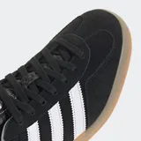 Championes Adidas Gazelle Indoor negros de gamuza con las tres tiras blancas y suela de goma color caramelo.