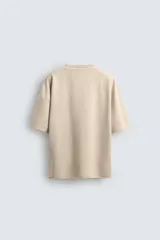 Camiseta color caqui de corte holgado, con cuello redondo y mangas cortas. Acabado con efecto lavado y ruedo irregular.